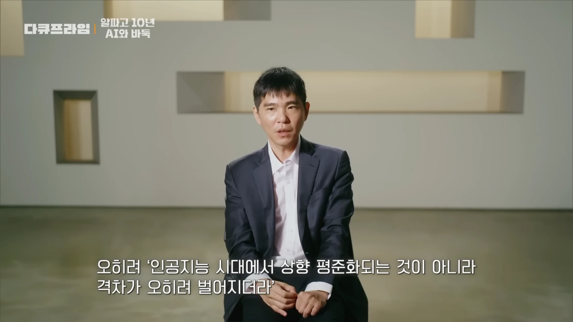 정장 차림으로 앉은 신진서 9단, 자막에 '인공지능 시대에 상향 평준화되는 것이 아니라 격차가 오히려 벌어지더라'
